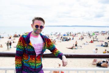 Man wearing a multicoloured hoodie and colourful face paints